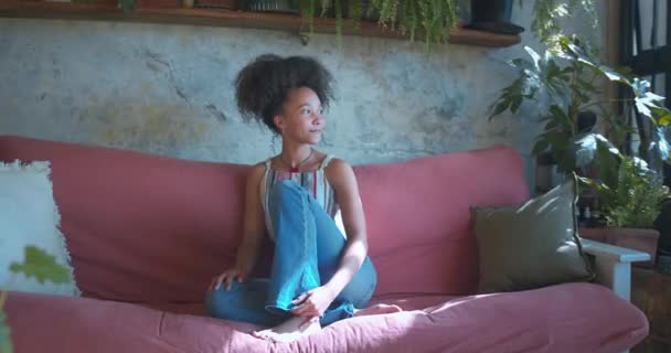 自宅のソファでリラックスしている美しいアフリカの若い女性のショット 高品質4K映像 — ストック動画
