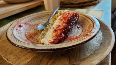 Cheesecake lezzetli bir meyve tatlısıdır. Dolgusu süzme peynir ya da mascarpone ile geliyor. Üstünde kırmızı böğürtlen reçeli var. Kırmızı tatlı reçel üstte. Meyveli kek tabakta. Yemek yakın planda..