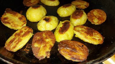 Kızarmış patates. Tavada patates yarımları. Vejetaryen ve vejetaryen yemekleri. Lezzetli meze. Yiyecekler yakın planda. Doğrudan yukarıdan bak. Tuzlu yemek. Mineraller ve vitaminler zengindir.