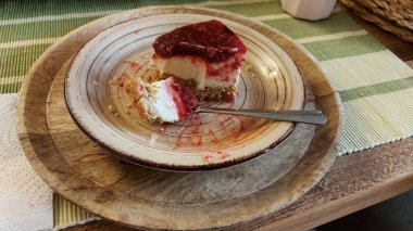 Cheesecake lezzetli bir meyve tatlısıdır. Dolgusu süzme peynir ya da mascarpone ile geliyor. Üstünde kırmızı böğürtlen reçeli var. Kırmızı tatlı reçel üstte. Meyveli kek tabakta. Yemek yakın planda..