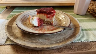 Cheesecake lezzetli bir meyve tatlısıdır. Dolgusu süzme peynir ya da mascarpone ile geliyor. Üstünde kırmızı böğürtlen reçeli var. Kırmızı tatlı reçel üstte. Meyveli kek tabakta. Yemek yakın planda..