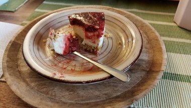 Cheesecake lezzetli bir meyve tatlısıdır. Dolgusu süzme peynir ya da mascarpone ile geliyor. Üstünde kırmızı böğürtlen reçeli var. Kırmızı tatlı reçel üstte. Meyveli kek tabakta. Yemek yakın planda..