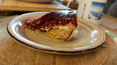 Cheesecake lezzetli bir meyve tatlısıdır. Dolgusu süzme peynir ya da mascarpone ile geliyor. Üstünde kırmızı böğürtlen reçeli var. Kırmızı tatlı reçel üstte. Meyveli kek tabakta. Yemek yakın planda..