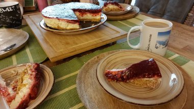 Cheesecake lezzetli bir meyve tatlısıdır. Dolgusu süzme peynir ya da mascarpone ile geliyor. Üstünde kırmızı böğürtlen reçeli var. Kırmızı tatlı reçel üstte. Meyveli kek tabakta. Yemek yakın planda..