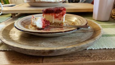 Cheesecake lezzetli bir meyve tatlısıdır. Dolgusu süzme peynir ya da mascarpone ile geliyor. Üstünde kırmızı böğürtlen reçeli var. Kırmızı tatlı reçel üstte. Meyveli kek tabakta. Yemek yakın planda..