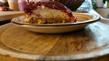 Cheesecake lezzetli bir meyve tatlısıdır. Dolgusu süzme peynir ya da mascarpone ile geliyor. Üstünde kırmızı böğürtlen reçeli var. Kırmızı tatlı reçel üstte. Meyveli kek tabakta. Yemek yakın planda..