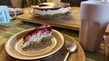 Cheesecake lezzetli bir meyve tatlısıdır. Dolgusu süzme peynir ya da mascarpone ile geliyor. Üstünde kırmızı böğürtlen reçeli var. Kırmızı tatlı reçel üstte. Meyveli kek tabakta. Yemek yakın planda..