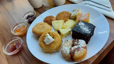 Ahşap arka planda kahve ve kek. Beyaz peçete. Kanabec keki. Ananas dilimleri. Meyve reçelli cam kaseler. Şeker şurubu tatlısı. Kalorili kekler. Doğulu tatlılar.