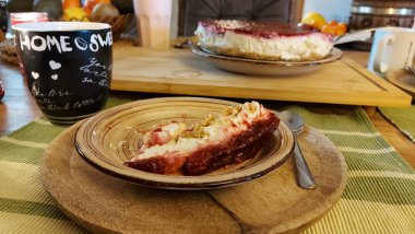 Cheesecake lezzetli bir meyve tatlısıdır. Dolgusu süzme peynir ya da mascarpone ile geliyor. Üstünde kırmızı böğürtlen reçeli var. Kırmızı tatlı reçel üstte. Meyveli kek tabakta. Yemek yakın planda..