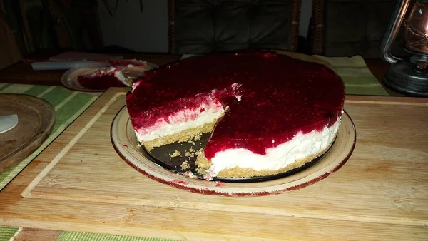 Cheesecake is a delicious fruit dessert. The filling comes with Cottage cheese or Mascarpone. It is topped with red berry jelly. The red sweet jam is on top. Fruitcake on the plate. Food in close up.