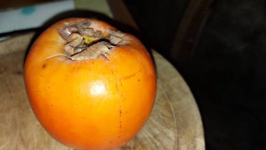 Tahta servis tabağında hurma meyvesi. Organik meyve. Hasattan sonra çiğ hurma. Meyveler vitamin doludur. Malların doğal bir meyvesi. Olgun ve tatlılar. Vejetaryen yiyecekler. Vejetaryen yemeği.