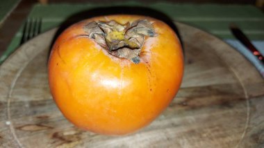 Tahta servis tabağında hurma meyvesi. Organik meyve. Hasattan sonra çiğ hurma. Meyveler vitamin doludur. Malların doğal bir meyvesi. Olgun ve tatlılar. Vejetaryen yiyecekler. Vejetaryen yemeği.