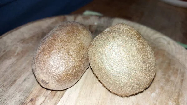 Tahta servis tabağında kivi. Organik meyve. Hasattan sonra çiğ kivi. Meyveler C vitaminleriyle doludur. Doğal ve eşsiz bir tadı var. Tatlı ve ekşi. Vejetaryen yiyecekler. Vejetaryen yemeği.