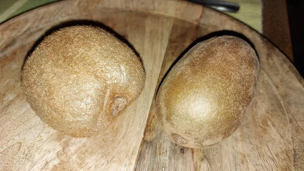 Tahta servis tabağında kivi. Organik meyve. Hasattan sonra çiğ kivi. Meyveler C vitaminleriyle doludur. Doğal ve eşsiz bir tadı var. Tatlı ve ekşi. Vejetaryen yiyecekler. Vejetaryen yemeği.