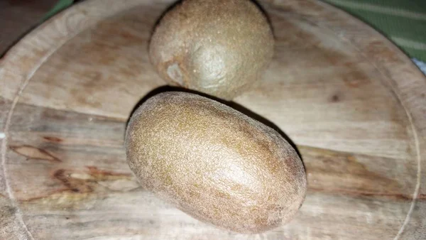 Tahta servis tabağında kivi. Organik meyve. Hasattan sonra çiğ kivi. Meyveler C vitaminleriyle doludur. Doğal ve eşsiz bir tadı var. Tatlı ve ekşi. Vejetaryen yiyecekler. Vejetaryen yemeği.