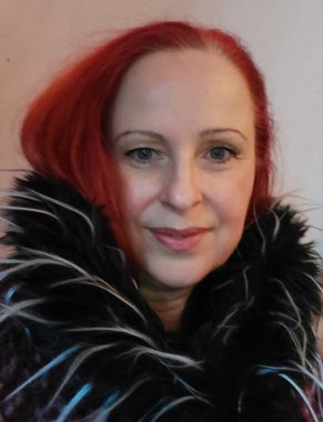 Female profile with fur winter clothes. A smiling face in close-up. Portrait with long red hair. A beautiful woman with green eyes. Winter scene.  Studio shot. A young adult. Wool scarf on the neck.