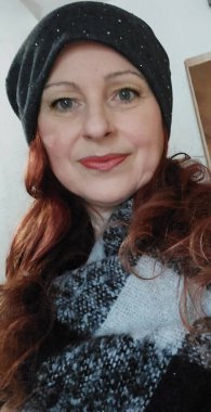 Female profile with a hat and scarf around her neck. Winter clothing. Smiling face close-up. Portrait with long red hair. A beautiful woman with green eyes. Winter scene. Studio shot. Young adult.