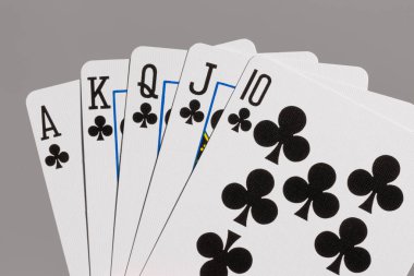 Close-up of poker hand showing royal flush in clubs