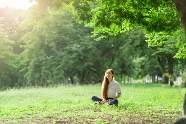 Asian woman wearing a white dress meditation in the park