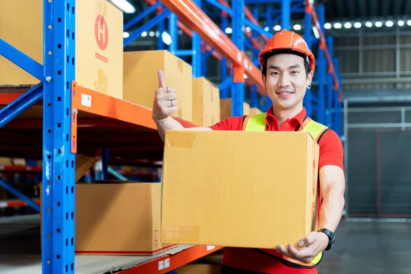 male worker with protective vest holds package, standing at warehouse of freight forwarding company
