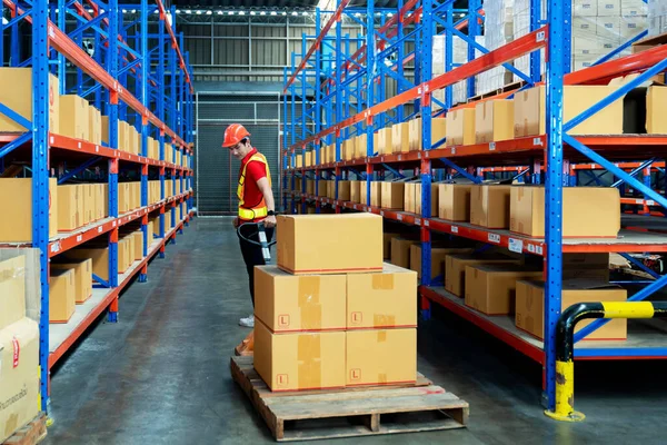 Worker wear safety helmet and holding clipboard and push cart in warehouse store. male warehouse worker checking storage box parcel in factory warehouse. Inspection quality control