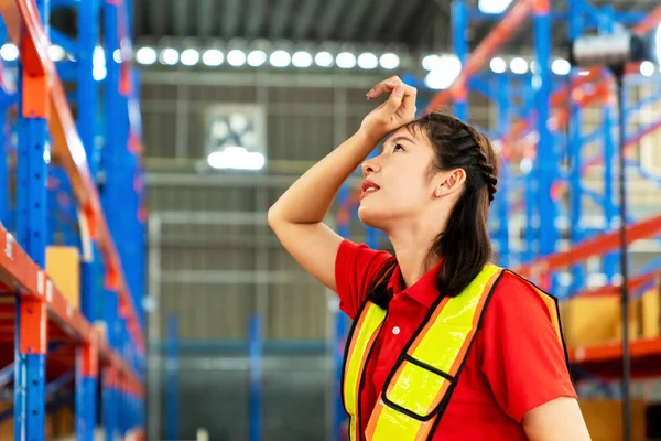 The female engineer was tired from work, was wiping her hands, wiping sweat on her face and standing at the forklift in a factory in Industrial Engineering worker concept