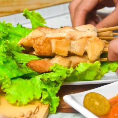 Sate Taichan, kızarmış tavuk, fıstık sosu ve soya sosu olmadan. Tabakta sambal (acı sos) ile servis edilir. Seçili odak.