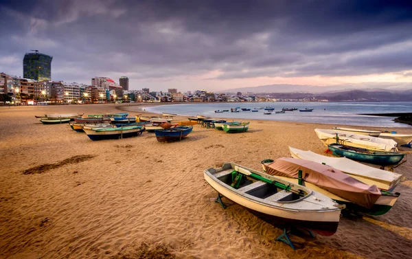 Las Canteras sahilinin gün batımı manzarası. Balıkçı tekneleri sarı kumlu arka plandaki binalar ve Atlantik Okyanusu Büyük Kanarya İspanya