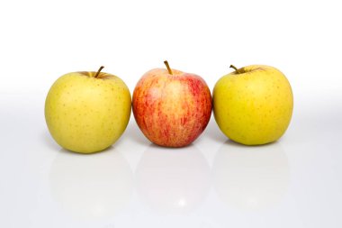 Bir fotoğraf stüdyosunda çekilmiş iki sarı elma ve bir kırmızı elma fotoğrafı.