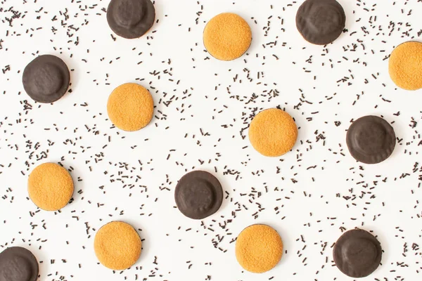 Sweet pattern made with chocolate cookies and chocolate sprinkles on white background. Chaotic flat lay. Process of making birthday cheesecake.