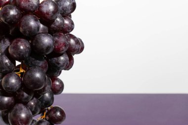 Beyaz ve mor arkaplandaki kırmızı üzümleri kapatın. Asgari meyve kavramı.