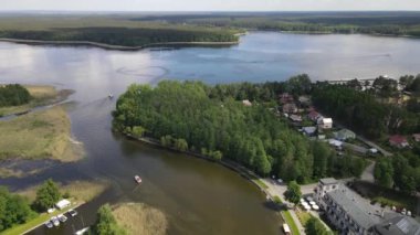 Panorama Augustowa z dron. Widok kanalu augustowskiego I plywajacych po nim statkow wycieczkowych, motorowek i zaglowek w letni sloneczny dzien.