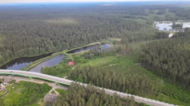 Güneşli bir yaz gününde göl ve ormanların arasında yol ve köprü üzerindeki drone 'dan görüntü.