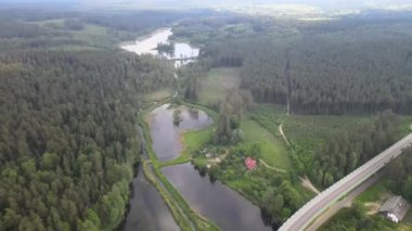 Güneşli bir yaz gününde göl ve ormanların arasında yol ve köprü üzerindeki drone 'dan görüntü.