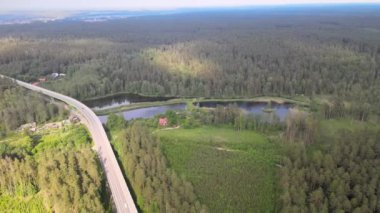 Güneşli bir yaz gününde göl ve ormanların arasında yol ve köprü üzerindeki drone 'dan görüntü.
