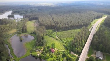 Güneşli bir yaz gününde göl ve ormanların arasında yol ve köprü üzerindeki drone 'dan görüntü.