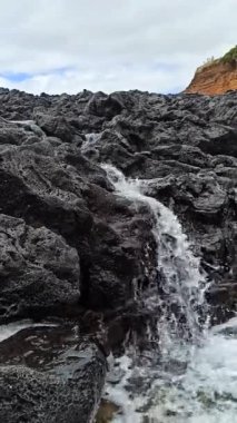 Dalgalardan sonra taştan bir sahilde küçük bir şelale.