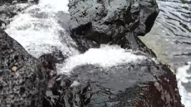 Dalgalardan sonra taştan bir sahilde küçük bir şelale.