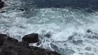 Terceira adasının güneşli havasında, taşların üzerinde dalgalar kırılır.