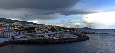 Atlantik Okyanusu 'ndaki Azores' de turuncu çatıları olan küçük bir kasabada çift gökkuşağı ile yağmurlu bir gün. Haziran 2022