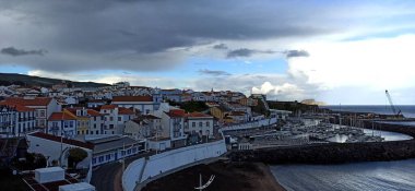 Atlantik Okyanusu 'ndaki Azores' de turuncu çatıları olan küçük bir kasabada çift gökkuşağı ile yağmurlu bir gün. Haziran 2022