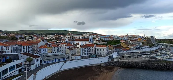 Atlantik Okyanusu 'ndaki Azores' de turuncu çatıları olan küçük bir kasabada çift gökkuşağı ile yağmurlu bir gün. Haziran 2022