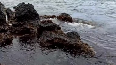 Terceira adasının güneşli havasında, taşların üzerinde dalgalar kırılır.