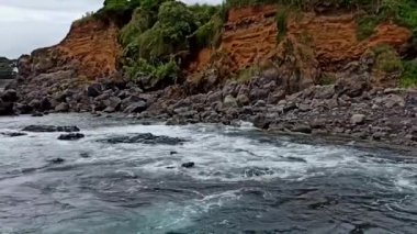 Terceira adasının güneşli havasında, taşların üzerinde dalgalar kırılır.