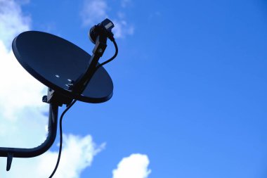 Mavi gökyüzü arkaplanlı çatıda TV siyah uydu anteni