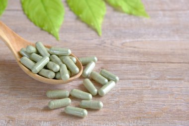 Andrographis Paniculata, Green Chiretta, bitkisel destek, ya da hastalık salgınında bağışıklık desteği için doğal bitkisel ilaçlar. Tahta kaşıkla kapsüle doldurulmuş, kahverengi plastik şişe.