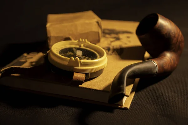 Denizci piposu olan bir kitabın üzerinde pusula