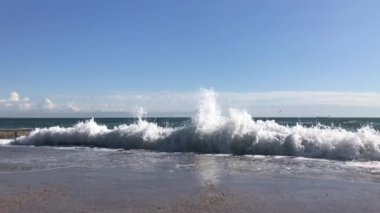 The sea wave slowly breaks on the pier.