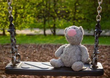 Plush children's toy on a swing in the park