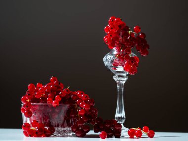 bunches of red currants in a glass bowl on a black background